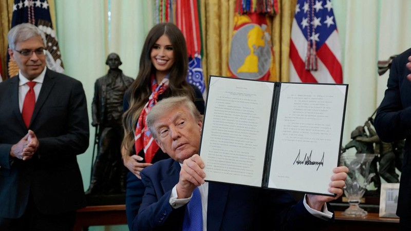 Presiden AS Donald Trump memperlihatkan perintah eksekutif yang telah ditandatangani terkait fleksibilitas vaksin, dengan Dr. Jay Bhattacharya, Direktur National Institutes of Health, berdiri di belakangnya, di Ruang Oval Gedung Putih di Washington, D.C., AS, pada 10 Agustus 2026.