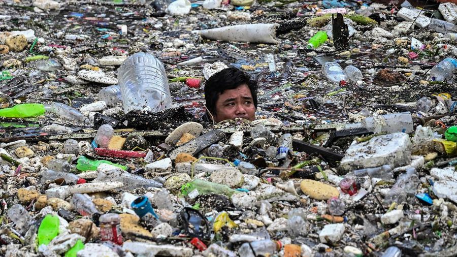 Seorang pekerja mengumpulkan sampah yang terbawa arus ke sungai di tengah hujan deras akibat angin muson barat daya di dekat Gereja Baclaran di Kota Paranaque, Metro Manila, Filipina, pada 11 Agustus 2026.
