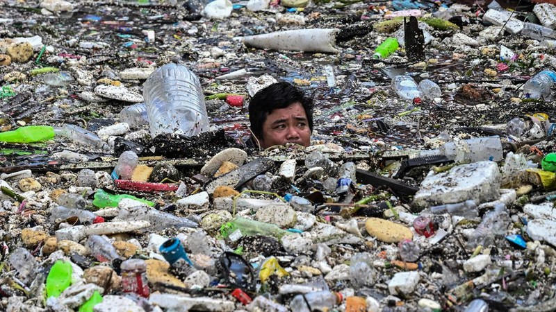 Seorang pekerja mengumpulkan sampah yang terbawa arus ke sungai di tengah hujan deras akibat angin muson barat daya di dekat Gereja Baclaran di Kota Paranaque, Metro Manila, Filipina, pada 11 Agustus 2026.