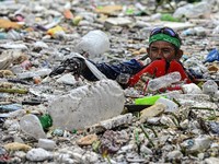 Seorang pekerja mengumpulkan sampah yang terbawa arus ke sungai di tengah hujan deras akibat angin muson barat daya, di dekat Gereja Baclaran di Kota Paranaque, Metro Manila, Filipina, 11 Agustus 2026. (REUTERS/NOEL CELIS)