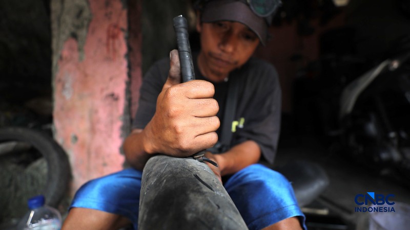Seorang pekerja menyelesaikan pengerikan ulang ban motor bekas (Vulkanisir) di Kawasan Beji, Depok, Jawa Barat, Selasa (11/8/2026). (CNBC Indonesia/Tri Susilo)