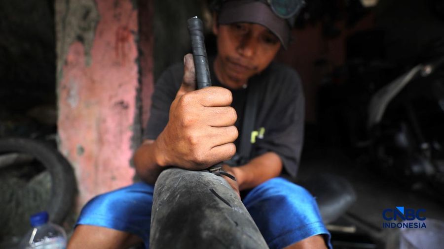 Seorang pekerja menyelesaikan pengerikan ulang ban motor bekas (Vulkanisir) di Kawasan Beji, Depok, Jawa Barat, Selasa (11/8/2026). (CNBC Indonesia/Tri Susilo)