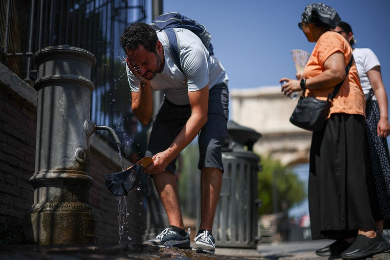 Seorang wanita menggunakan payung untuk berlindung dari terik matahari saat mengunjungi Forum Romawi di tengah suhu yang mendekati 40 derajat Celsius akibat gelombang panas, di Roma, Italia, pada 11 Agustus 2026. (REUTERS/Guglielmo Mangiapane)