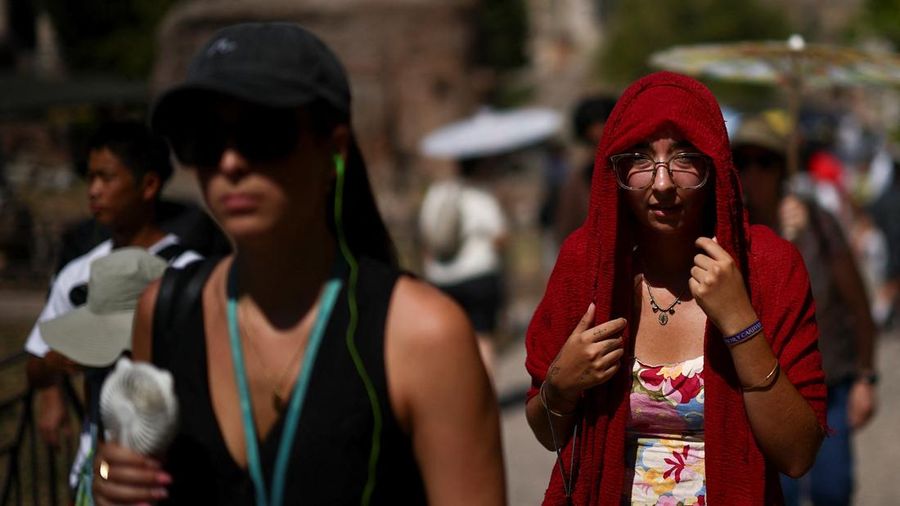Seorang wanita menutupi kepalanya untuk berlindung dari sinar matahari saat mengunjungi Forum Romawi di tengah suhu yang mendekati 40 derajat Celsius akibat gelombang panas, di Roma, Italia, 11 Agustus 2026.