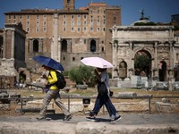 Warga menggunakan payung untuk berlindung dari terik matahari saat mengunjungi Forum Romawi di tengah suhu yang mendekati 40 derajat Celsius akibat gelombang panas, di Roma, Italia, 11 Agustus 2026. (REUTERS/Guglielmo Mangiapane)