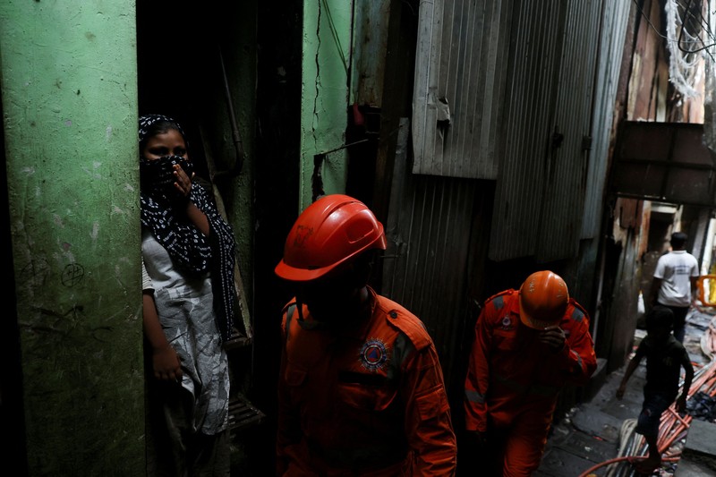 Warga menyaksikan petugas Pasukan Tanggap Bencana Nasional (NDRF) berjalan menuju lokasi tanah longsor setelah sebagian bukit runtuh menimpa rumah-rumah di kawasan permukiman kumuh di Mumbai, India, pada 12 Agustus 2026. (REUTERS/Francis Mascarenhas)