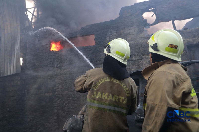 Sejumlah petugas pemadam kebakaran berusaha memadamkan api di sebuah pabrik bingkai yang terbakar, di Jalan Lampiri, Jakarta Timur, Rabu (12/08/2026). (CNBC Indonesia/Muhammad Sabki)