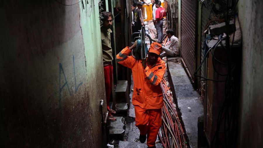 Seorang personel Pasukan Tanggap Bencana Nasional (NDRF) membawa peralatan pemotong sembari berjalan menuju lokasi tanah longsor, setelah sebagian bukit runtuh menimpa rumah-rumah di kawasan permukiman padat penduduk di Mumbai, India, pada 12 Agustus 2026.