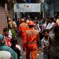 Warga menyaksikan petugas Pasukan Tanggap Bencana Nasional (NDRF) berjalan menuju lokasi tanah longsor setelah sebagian bukit runtuh menimpa rumah-rumah di kawasan permukiman kumuh di Mumbai, India, pada 12 Agustus 2026. (REUTERS/Francis Mascarenhas)