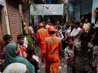 Warga menyaksikan petugas Pasukan Tanggap Bencana Nasional (NDRF) berjalan menuju lokasi tanah longsor setelah sebagian bukit runtuh menimpa rumah-rumah di kawasan permukiman kumuh di Mumbai, India, pada 12 Agustus 2026. (REUTERS/Francis Mascarenhas)