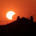 Bulan menutupi sebagian Matahari di atas sebuah atap saat gerhana matahari, sebagaimana terlihat dari Beograd, Serbia, pada 12 Agustus 2026. (REUTERS/Djordje Kojadinovic)