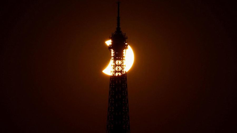 Menara Eiffel tampak dalam siluet saat bulan menutupi sebagian matahari selama gerhana matahari, sebagaimana terlihat dari Paris, Prancis, pada 12 Agustus 2026.
