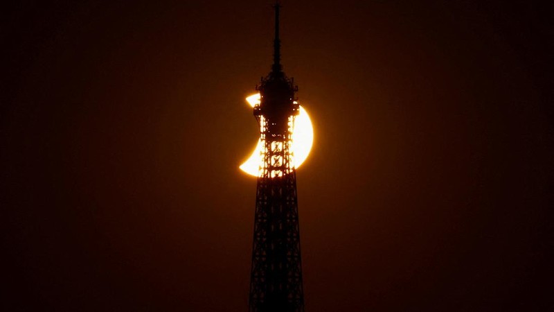 Menara Eiffel tampak dalam siluet saat bulan menutupi sebagian matahari selama gerhana matahari, sebagaimana terlihat dari Paris, Prancis, pada 12 Agustus 2026.