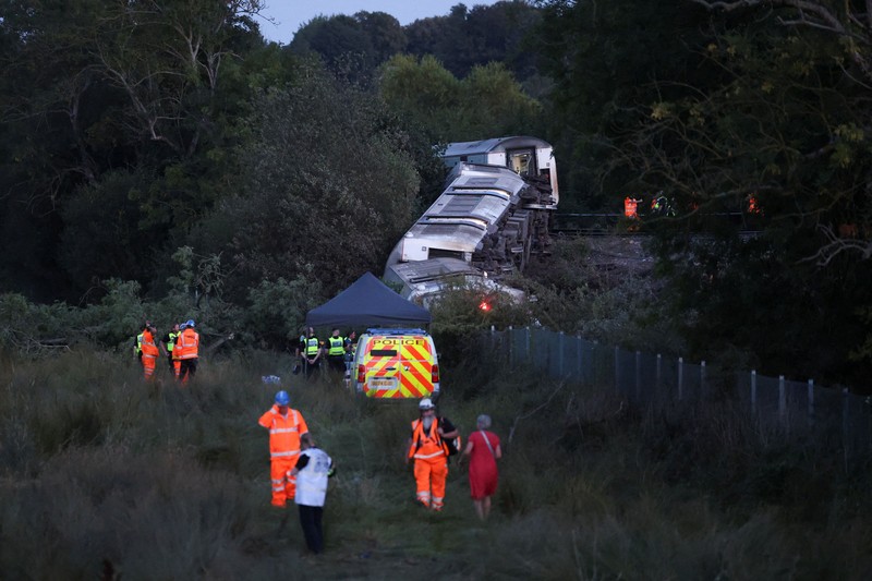 Petugas darurat bekerja di lokasi kejadian di samping kereta yang terguling setelah kereta penumpang layanan Southern tergelincir di dekat Lewes, Inggris tenggara, Kamis (13/8/2026). (REUTERS/Toby Shepheard)