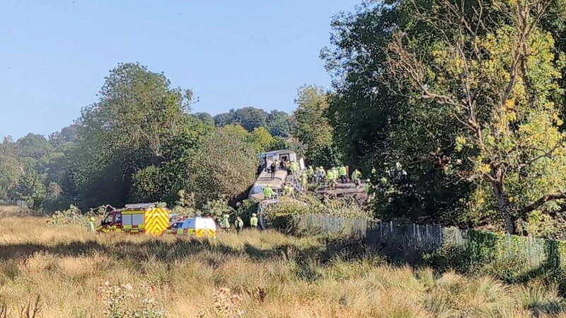 Petugas darurat bekerja di lokasi kejadian di samping kereta yang terguling setelah kereta penumpang layanan Southern tergelincir di dekat Lewes, Inggris tenggara, Kamis (13/8/2026). (X/via REUTERS)