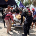 Petugas kepolisian membantu memindahkan seorang pasien ke tempat penampungan di area terbuka sebuah rumah sakit, menyusul gempa bumi yang terasa di Labuan Bajo, Provinsi Nusa Tenggara Timur, Indonesia, Minggu (15/8/2026). (REUTERS/Stringer)