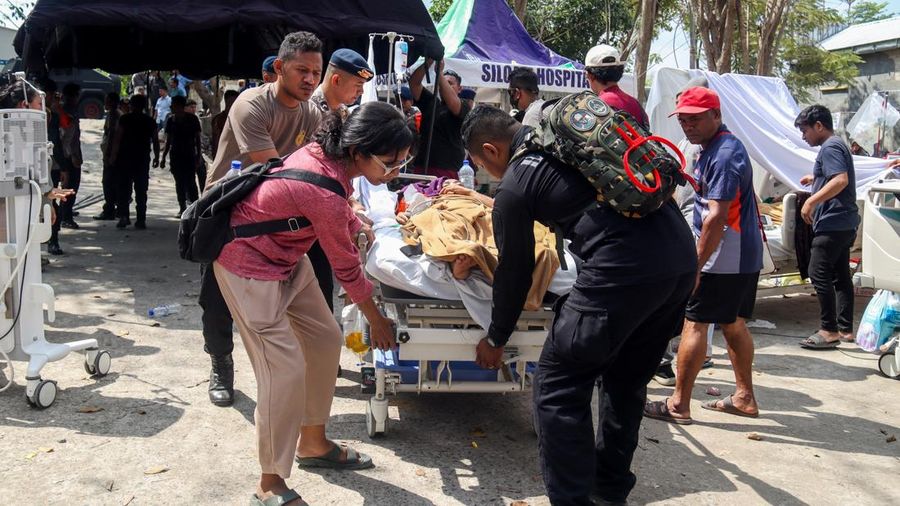 Petugas kepolisian membantu memindahkan seorang pasien ke tempat penampungan di area terbuka sebuah rumah sakit, menyusul gempa bumi yang terasa di Labuan Bajo, Provinsi Nusa Tenggara Timur, Indonesia, Minggu (15/8/2026). (REUTERS/Stringer)