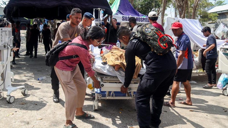 Petugas kepolisian membantu memindahkan seorang pasien ke tempat penampungan di area terbuka sebuah rumah sakit, menyusul gempa bumi yang terasa di Labuan Bajo, Provinsi Nusa Tenggara Timur, Indonesia, Minggu (15/8/2026). (REUTERS/Stringer)