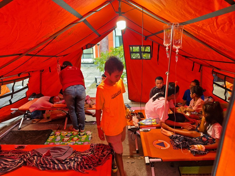 Warga desa duduk di bawah tenda darurat setelah mengungsi ke perbukitan menyusul gempa bumi yang terasa di Sikka, Indonesia, Minggu (16/8/2026). (REUTERS/Stringer)