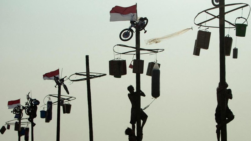 Para peserta berusaha mencapai puncak tiang yang dilumuri pelumas untuk mengambil hadiah dalam lomba