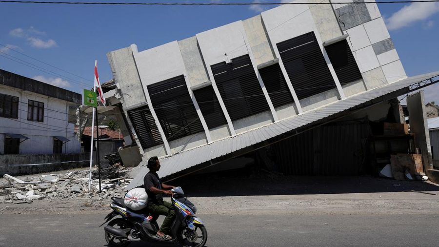 Seorang pria mengendarai motor melintasi sebuah swalayan yang runtuh akibat gempa bumi di Reok, Provinsi Nusa Tenggara Timur, Indonesia, 18 Agustus 2026. REUTERS/Willy Kurniawan