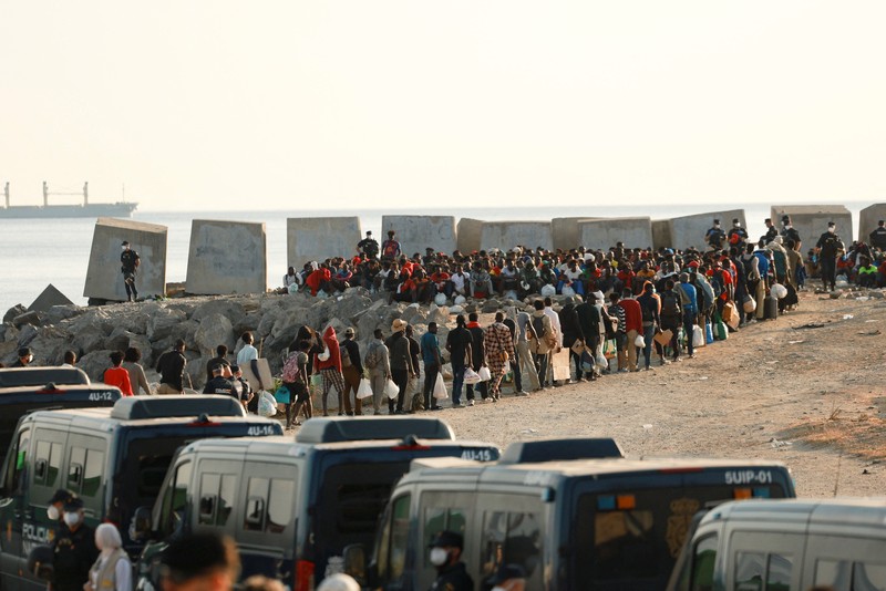 Para migran dikawal dari kamp darurat di pantai menuju tempat penampungan resmi di berbagai lokasi di kota tersebut setelah pihak berwenang membersihkan area itu&mdash;menyusul penyeberangan massal dari Maroko&mdash;di wilayah kantong Spanyol di Afrika Utara, Ceuta, pada 20 Agustus 2026. (REUTERS/Violeta Santos Moura)