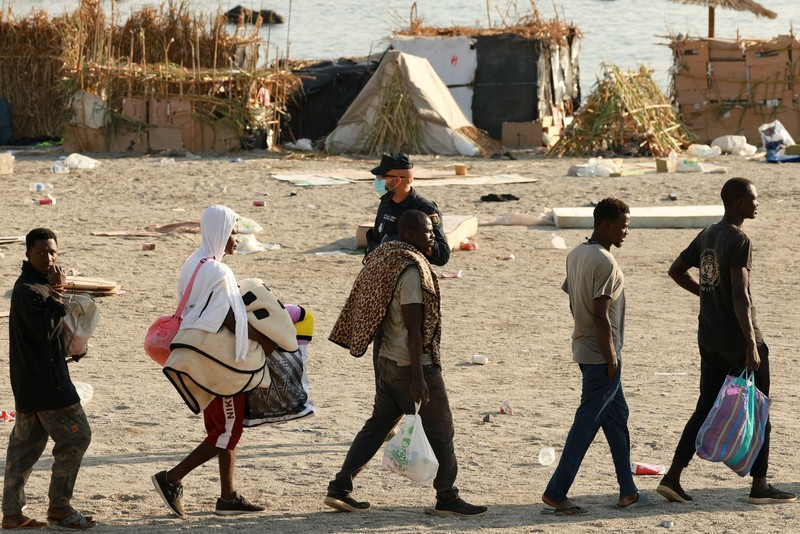 Para migran dikawal dari kamp darurat di pantai menuju tempat penampungan resmi di berbagai lokasi di kota tersebut setelah pihak berwenang membersihkan area itu&mdash;menyusul penyeberangan massal dari Maroko&mdash;di wilayah kantong Spanyol di Afrika Utara, Ceuta, pada 20 Agustus 2026. (REUTERS/Violeta Santos Moura)