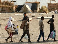 Para migran dikawal dari kamp darurat di pantai menuju tempat penampungan resmi di berbagai lokasi di kota tersebut setelah pihak berwenang membersihkan area itumenyusul penyeberangan massal dari Marokodi wilayah kantong Spanyol di Afrika Utara, Ceut