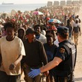 Para migran dikawal dari kamp darurat di pantai menuju tempat penampungan resmi di berbagai lokasi di kota tersebut setelah pihak berwenang membersihkan area itumenyusul penyeberangan massal dari Marokodi wilayah kantong Spanyol di Afrika Utara, Ceut