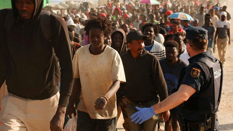 Para migran dikawal dari kamp darurat di pantai menuju tempat penampungan resmi di berbagai lokasi di kota tersebut setelah pihak berwenang membersihkan area itumenyusul penyeberangan massal dari Marokodi wilayah kantong Spanyol di Afrika Utara, Ceut