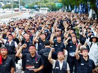 Anggota Serikat Pekerja Logam Korea mengangkat kepalan tangan mereka dalam sebuah unjuk rasa di luar kantor pusat Hyundai Motor Company saat serikat pekerja perusahaan otomotif tersebut menggelar pemogokan kerja total pertamanya dalam satu dekade, di