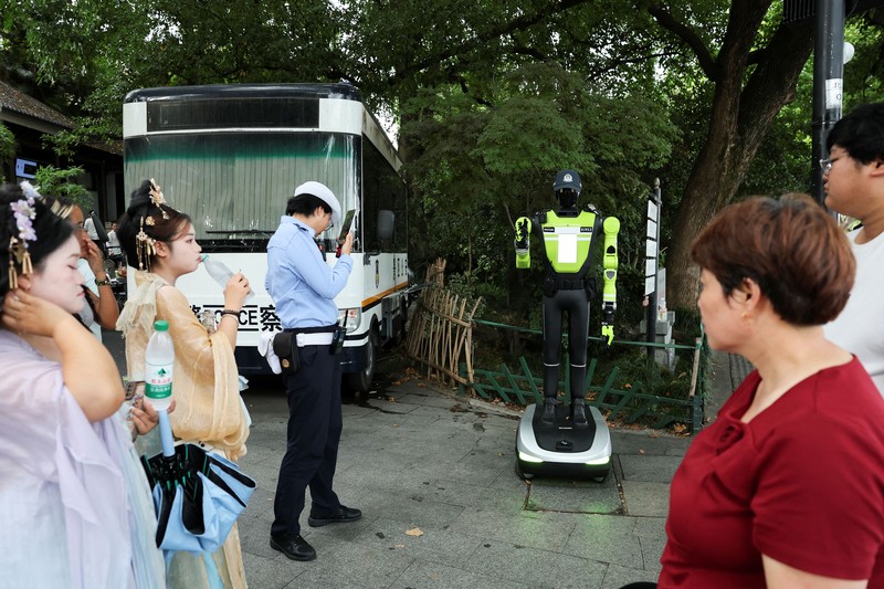 Sebuah robot polisi lalu lintas berbentuk manusia yang dikembangkan oleh SUPCON sedang bertugas di sebuah jalan di Hangzhou, Provinsi Zhejiang, China, pada 21 Juli 2026. (REUTERS/Go Nakamura)