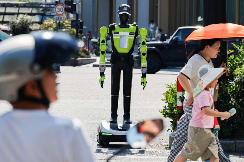 Sebuah robot polisi lalu lintas berbentuk manusia yang dikembangkan oleh SUPCON sedang bertugas di sebuah jalan di Hangzhou, Provinsi Zhejiang, China, pada 21 Juli 2026. (REUTERS/Go Nakamura)
