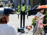 Orang-orang berjalan melewati robot polisi lalu lintas berbentuk manusia yang dikembangkan oleh SUPCON saat robot tersebut sedang bertugas di sebuah jalan di Hangzhou, Provinsi Zhejiang, China, pada 31 Juli 2026. (REUTERS/Go Nakamura)
