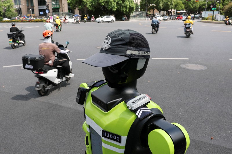 Sebuah robot polisi lalu lintas berbentuk manusia yang dikembangkan oleh SUPCON sedang bertugas di sebuah jalan di Hangzhou, Provinsi Zhejiang, China, pada 21 Juli 2026. (REUTERS/Go Nakamura)