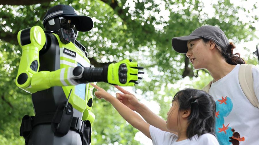 Warga menyentuh layar pada robot polisi lalu lintas berbentuk manusia yang dikembangkan oleh SUPCON saat robot tersebut sedang bertugas di sebuah jalan di Hangzhou, Provinsi Zhejiang, China, pada 21 Juli 2026.