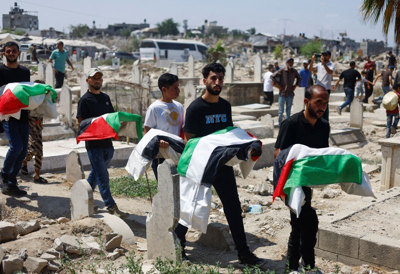 Warga Palestina mengusung peti jenazah saat menghadiri pemakaman 50 orang dari tiga keluarga yang tewas dalam perang dan jenazahnya baru-baru ini dievakuasi dari bawah reruntuhan, di Kota Gaza, 20 Agustus 2026. (REUTERS/Mahmoud Issa)