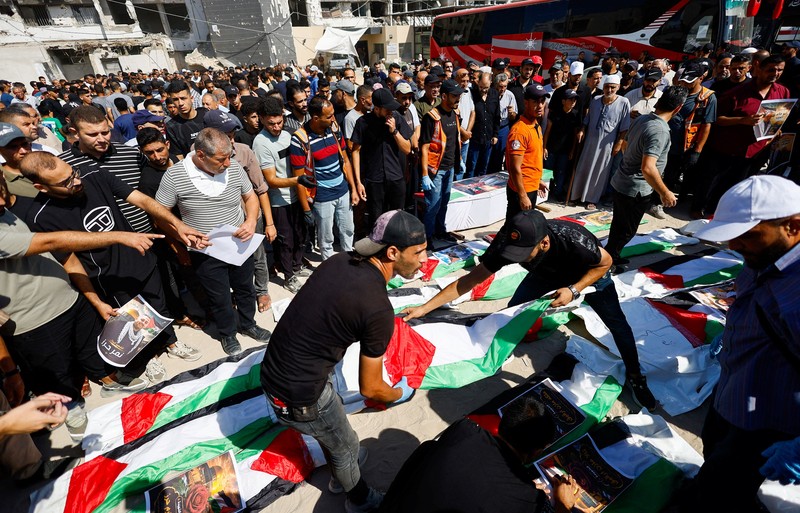 Warga Palestina mengusung peti jenazah saat menghadiri pemakaman 50 orang dari tiga keluarga yang tewas dalam perang dan jenazahnya baru-baru ini dievakuasi dari bawah reruntuhan, di Kota Gaza, 20 Agustus 2026. (REUTERS/Mahmoud Issa)