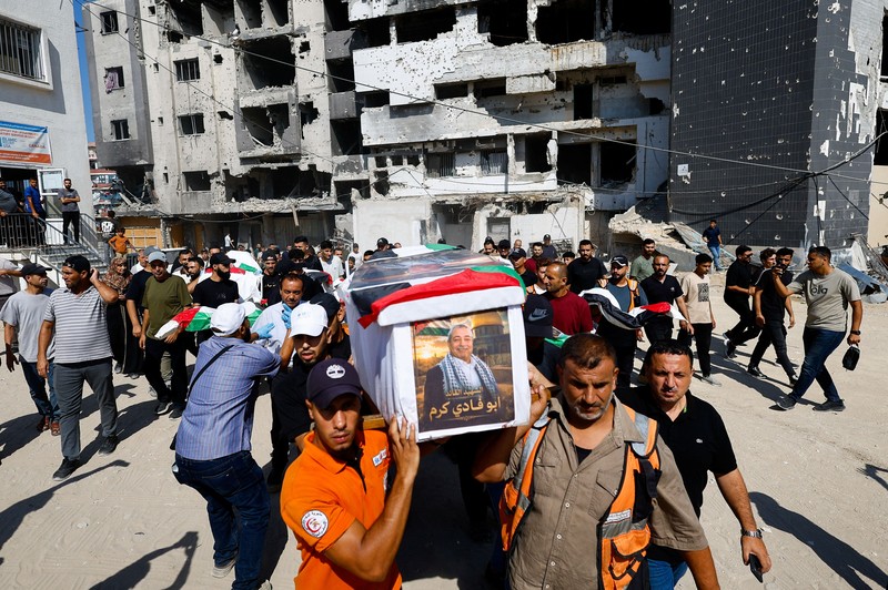 Warga Palestina mengusung peti jenazah saat menghadiri pemakaman 50 orang dari tiga keluarga yang tewas dalam perang dan jenazahnya baru-baru ini dievakuasi dari bawah reruntuhan, di Kota Gaza, 20 Agustus 2026. (REUTERS/Mahmoud Issa)