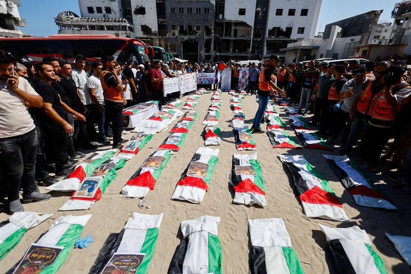 Warga Palestina mengusung peti jenazah saat menghadiri pemakaman 50 orang dari tiga keluarga yang tewas dalam perang dan jenazahnya baru-baru ini dievakuasi dari bawah reruntuhan, di Kota Gaza, 20 Agustus 2026. (REUTERS/Mahmoud Issa)