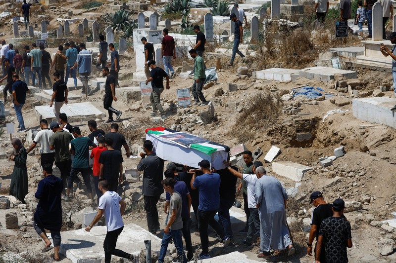 Warga Palestina mengusung peti jenazah saat menghadiri pemakaman 50 orang dari tiga keluarga yang tewas dalam perang dan jenazahnya baru-baru ini dievakuasi dari bawah reruntuhan, di Kota Gaza, 20 Agustus 2026. (REUTERS/Mahmoud Issa)