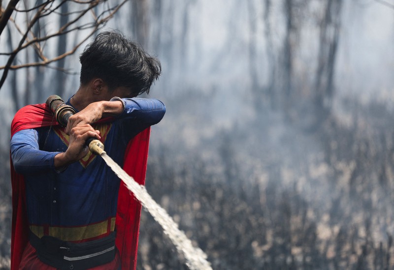 Rudiyansah, 16 tahun, mengenakan kostum Superman saat memadamkan api di area yang terdampak kebakaran hutan dan lahan di Palangka Raya, Provinsi Kalimantan Tengah, Jumat (14/8/2026). (REUTERS/Ajeng Dinar Ulfiana)