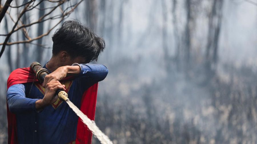 Rudiyansah, 16 tahun, mengenakan kostum Superman saat memadamkan api di area nan terdampak kebakaran rimba dan lahan di Palangka Raya, Provinsi Kalimantan Tengah, Jumat (14/8/2026). (REUTERS/Ajeng Dinar Ulfiana)
