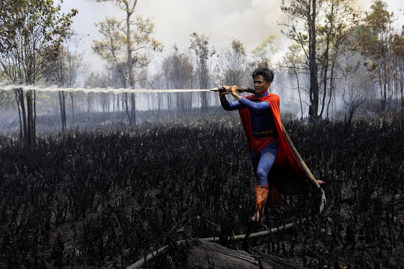 Rudiyansah, 16 tahun, mengenakan kostum Superman saat memadamkan api di area yang terdampak kebakaran hutan dan lahan di Palangka Raya, Provinsi Kalimantan Tengah, Jumat (14/8/2026). (REUTERS/Ajeng Dinar Ulfiana)