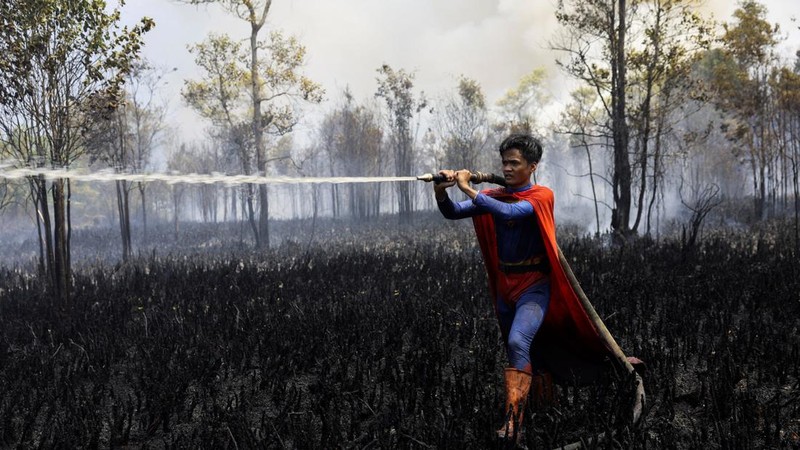 Rudiyansah, 16 tahun, mengenakan kostum Superman saat memadamkan api di area yang terdampak kebakaran hutan dan lahan di Palangka Raya, Provinsi Kalimantan Tengah, Jumat (14/8/2026). (REUTERS/Ajeng Dinar Ulfiana)