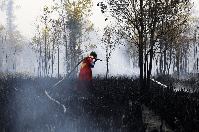 Rudiyansah, 16 tahun, mengenakan kostum Superman saat memadamkan api di area yang terdampak kebakaran hutan dan lahan di Palangka Raya, Provinsi Kalimantan Tengah, Jumat (14/8/2026). (REUTERS/Ajeng Dinar Ulfiana)