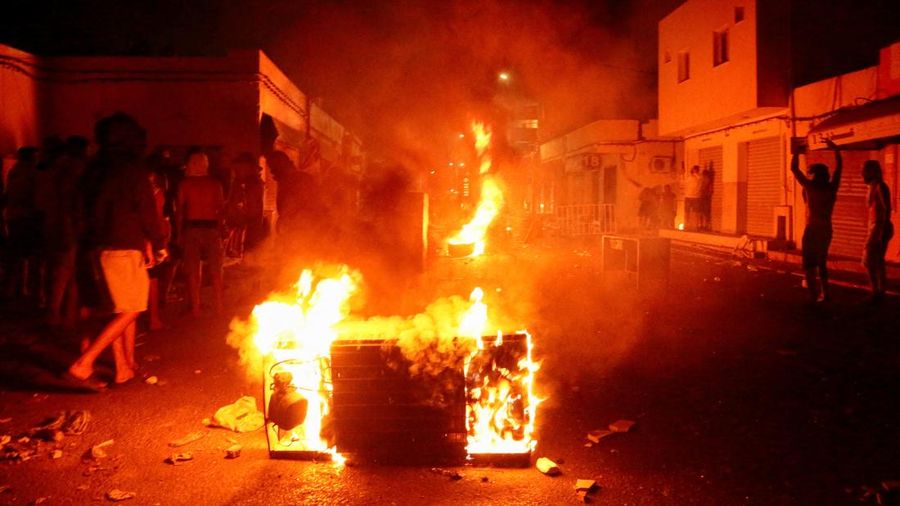 Api berkobar di jalan saat para pengunjuk rasa bentrok dengan aparat keamanan dalam sebuah aksi protes, menyusul tenggelamnya kapal migran yang menuju Italia, di Ben Guerdane, Tunisia, 24 Agustus 2026.