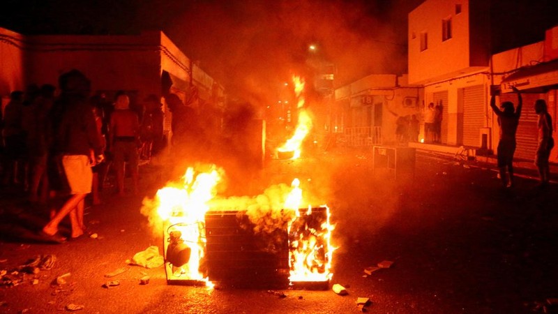 Api berkobar di jalan saat para pengunjuk rasa bentrok dengan aparat keamanan dalam sebuah aksi protes, menyusul tenggelamnya kapal migran yang menuju Italia, di Ben Guerdane, Tunisia, 24 Agustus 2026.