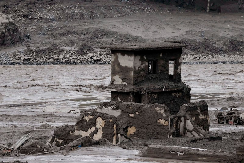 Warga berdiri di dekat rumah-rumah yang tertutup lumpur dan sebuah jalan setelah banjir bandang di Trishuli, Distrik Nuwakot, Nepal, pada 26 Agustus 2026. (REUTERS/Navesh Chitrakar)
