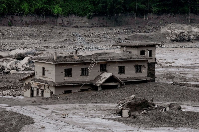 Warga berdiri di dekat rumah-rumah yang tertutup lumpur dan sebuah jalan setelah banjir bandang di Trishuli, Distrik Nuwakot, Nepal, pada 26 Agustus 2026. (REUTERS/Navesh Chitrakar)